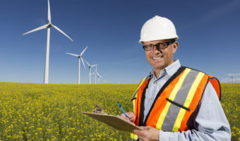 Man in field next to wind turbines