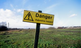 Danger Asbestos Hazard Yellow sign - Field in the background